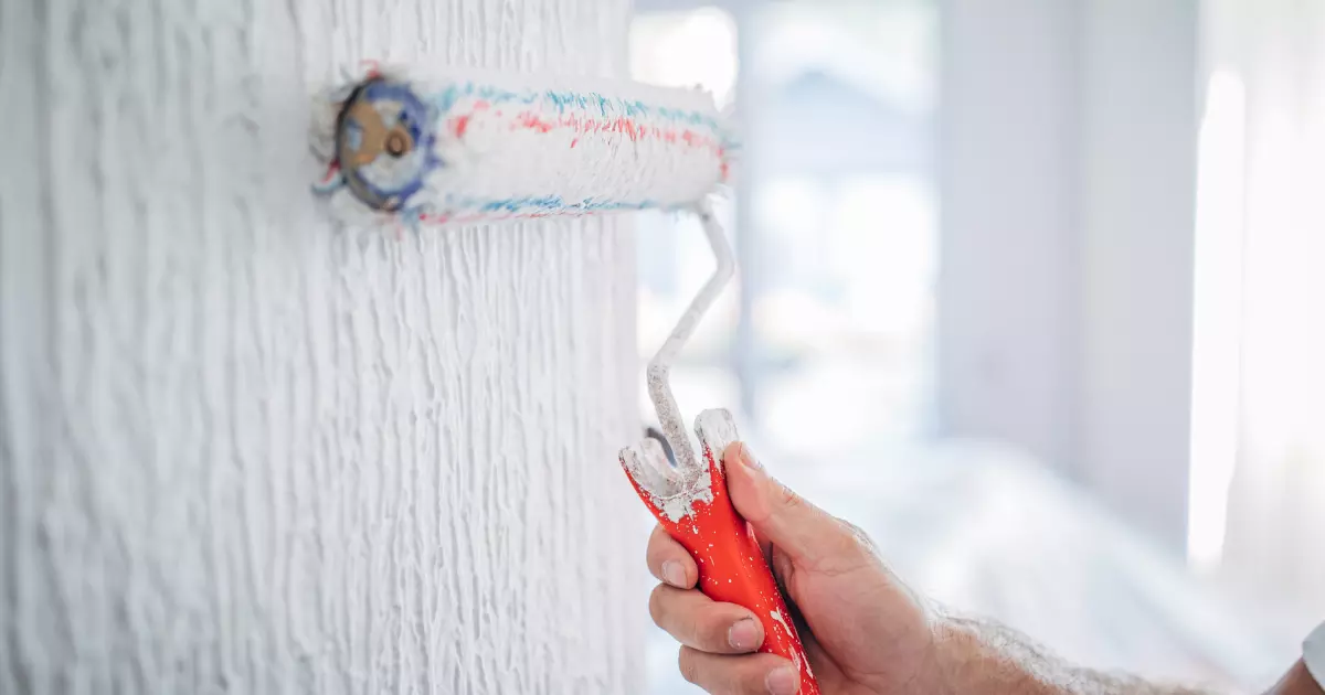 hand painting a white wall using roller brush